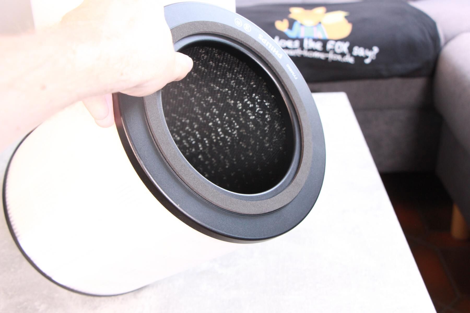  Блок фильтра воздухоочистителя Philips Air Performer 7000 держится в руке рядом с прибором, снаружи виден HEPA-фильтр, а внутри - фильтр из активированного угля.